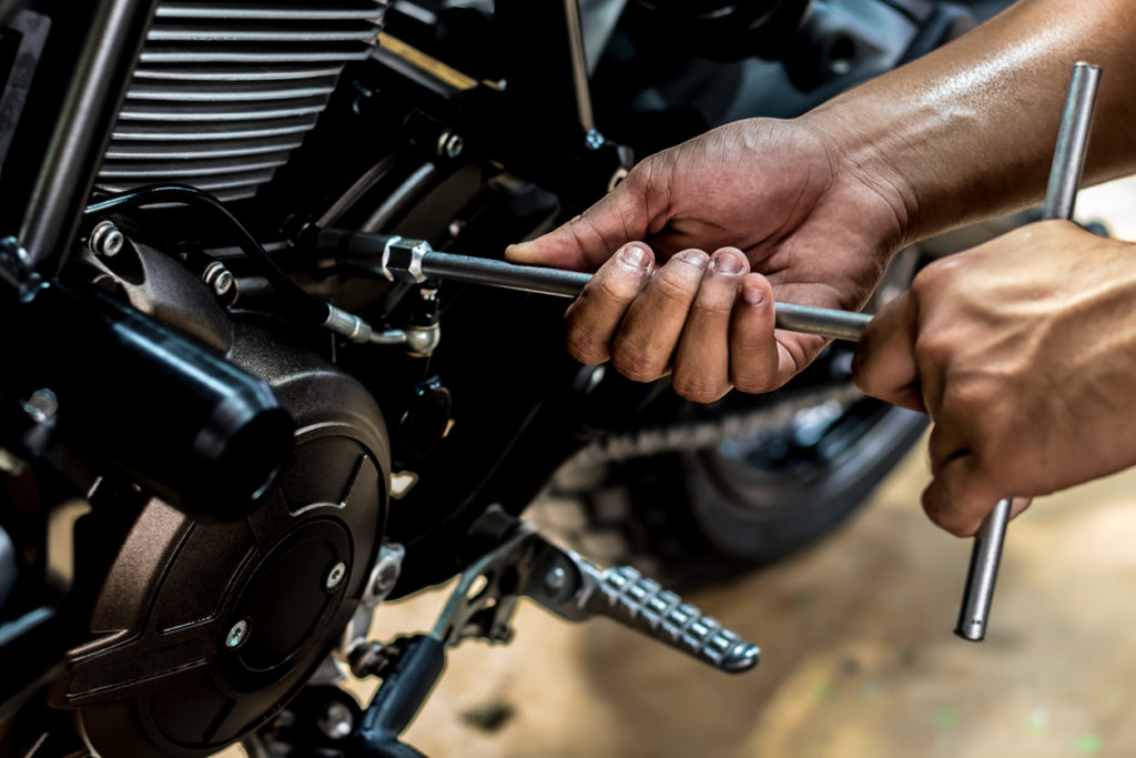 Gente tomándose de la mano reparando una motocicleta. Use una llave inglesa y un destornillador para operar.