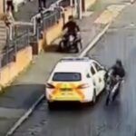 El conductor de la scooter patea el coche de policía, pero el coche de policía retrocede
